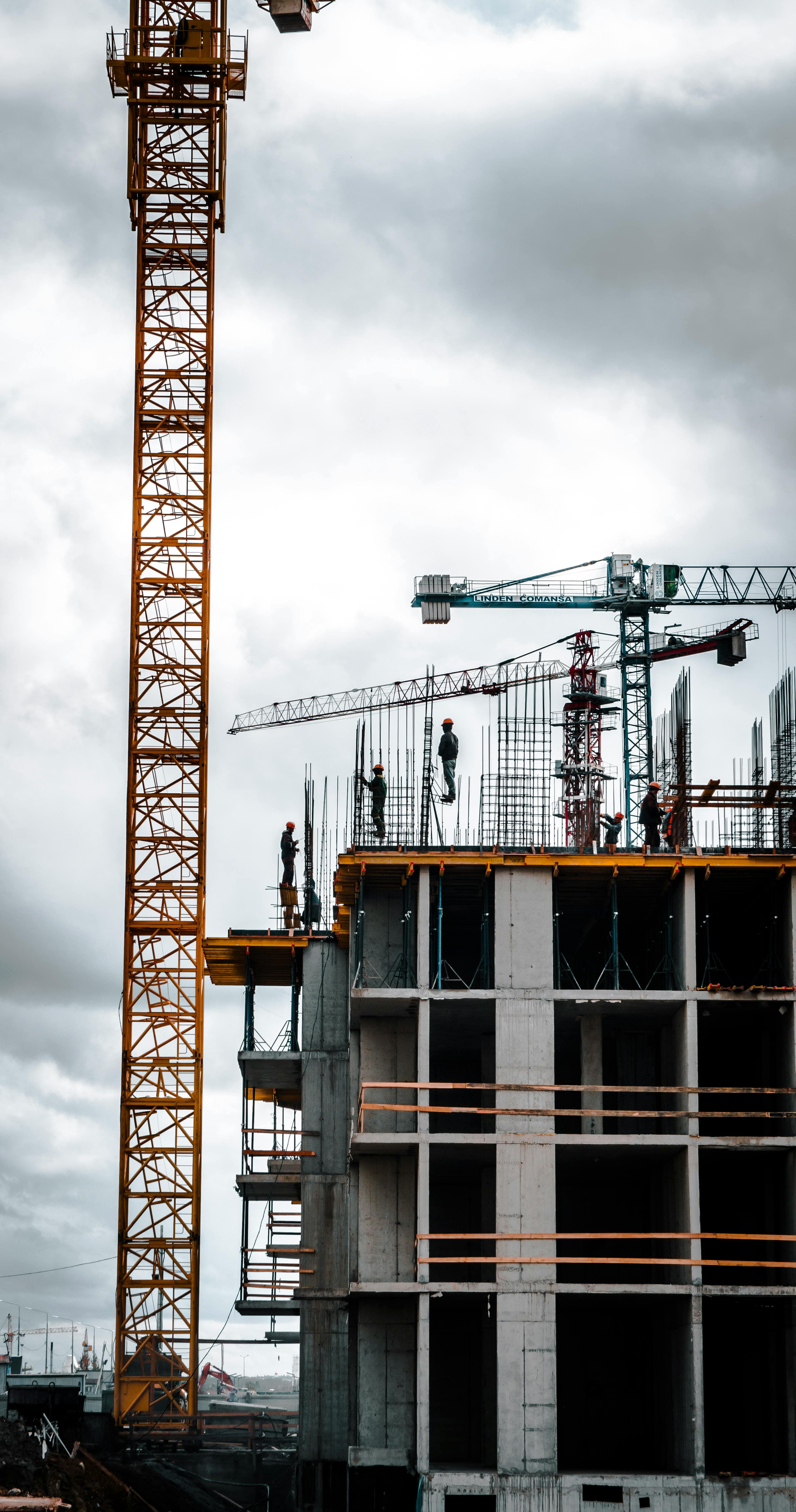 Grues et chantier d'immeuble en construction sous ciel chargé